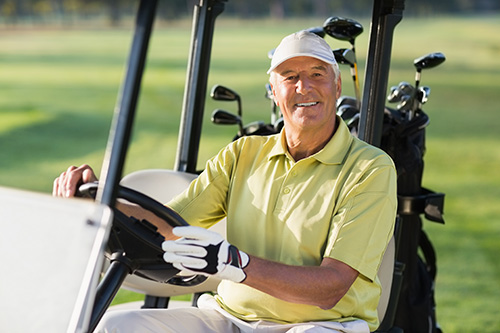 A Man smiling while driving inside of the golf club