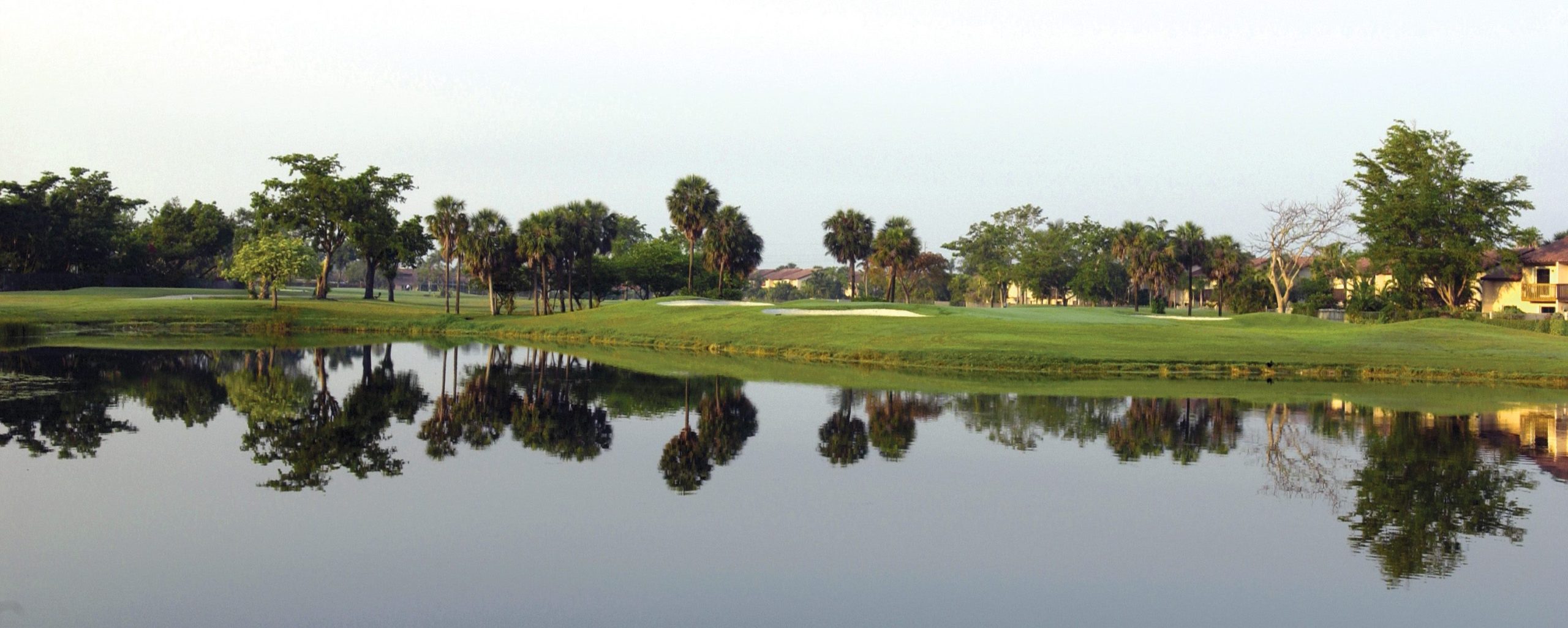 The golf course features a lake and numerous trees