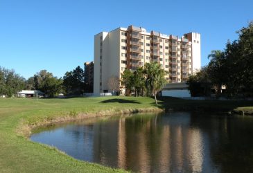 There is a lake and a building on the golf course - Elison Senior Living of Pinecrest