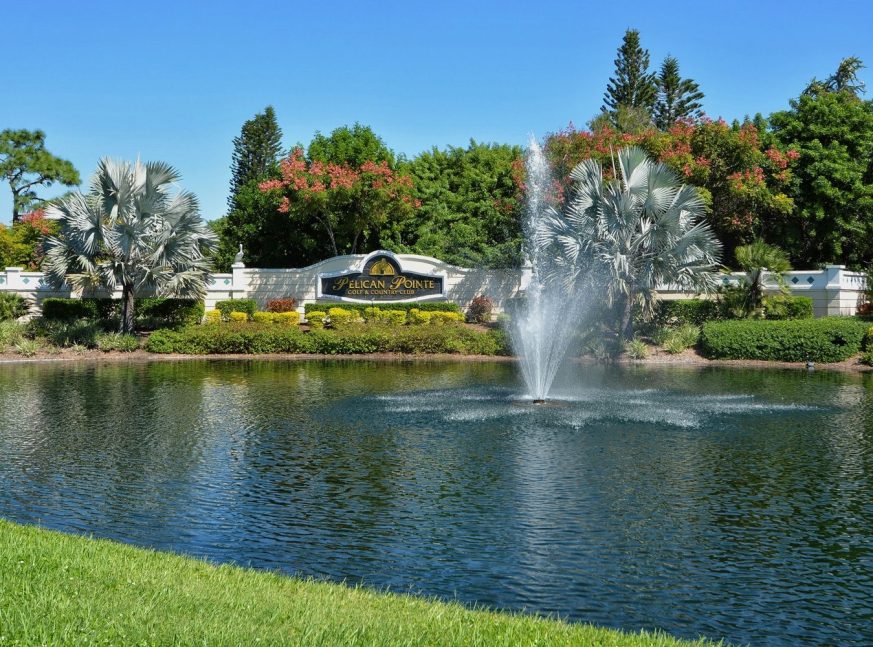 There is a lake with a fountain on the golf course