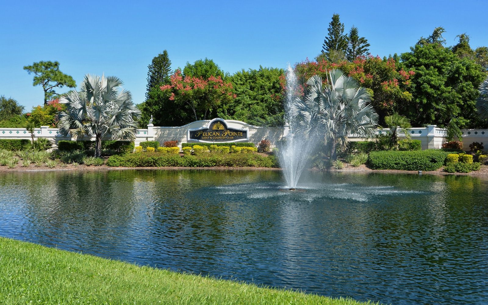 There is a lake with a fountain on the golf course