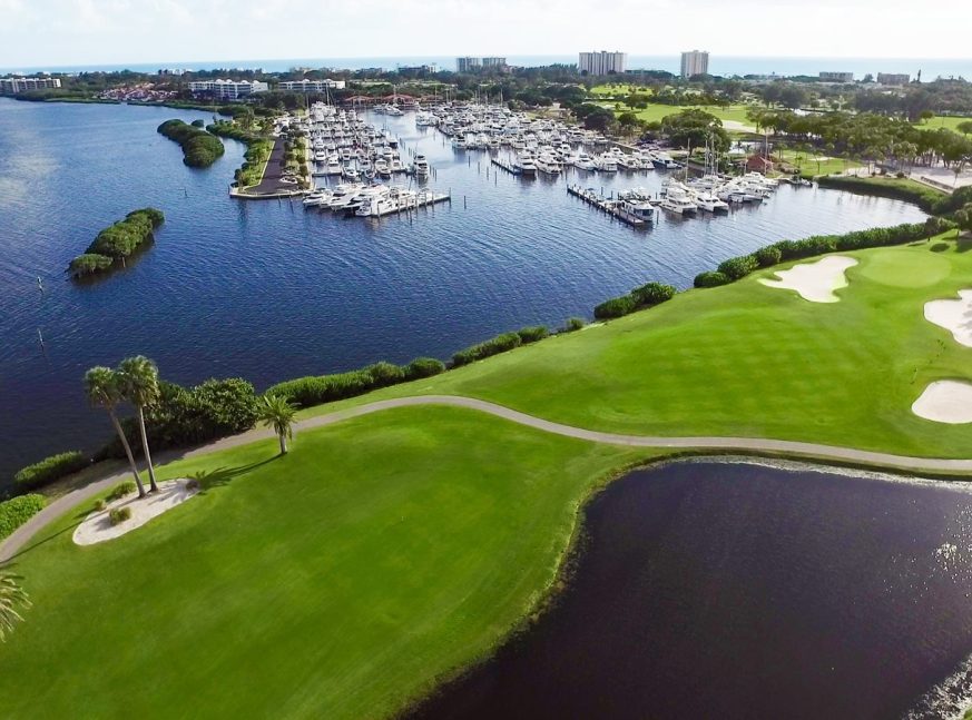 There are many boats moored in the sea, and the Longboat Key Golf Club has a golf course