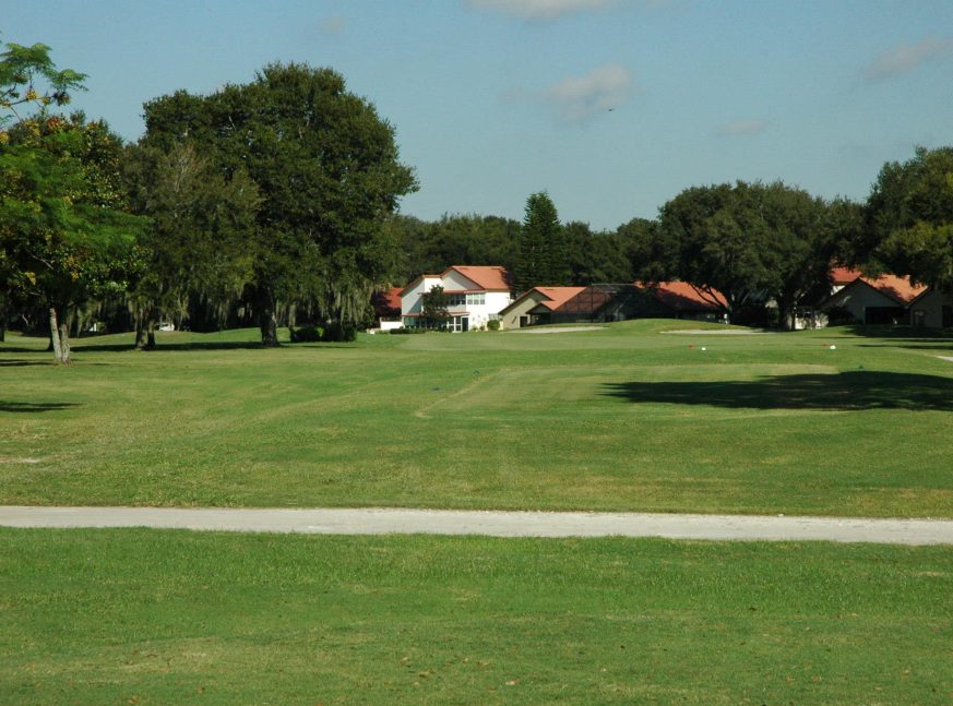At the back, there is a golf course surrounded by trees and houses.