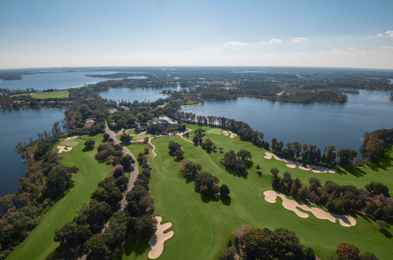 Aerial view of the golf course's lakes and homes, with many trees.