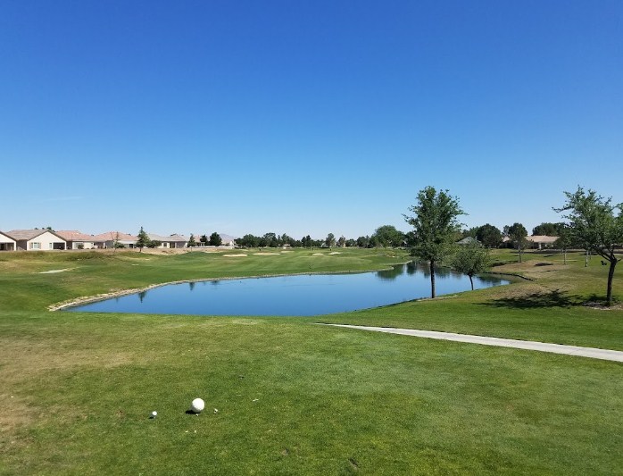On the golf course, there are lakes, homes, and numerous trees.