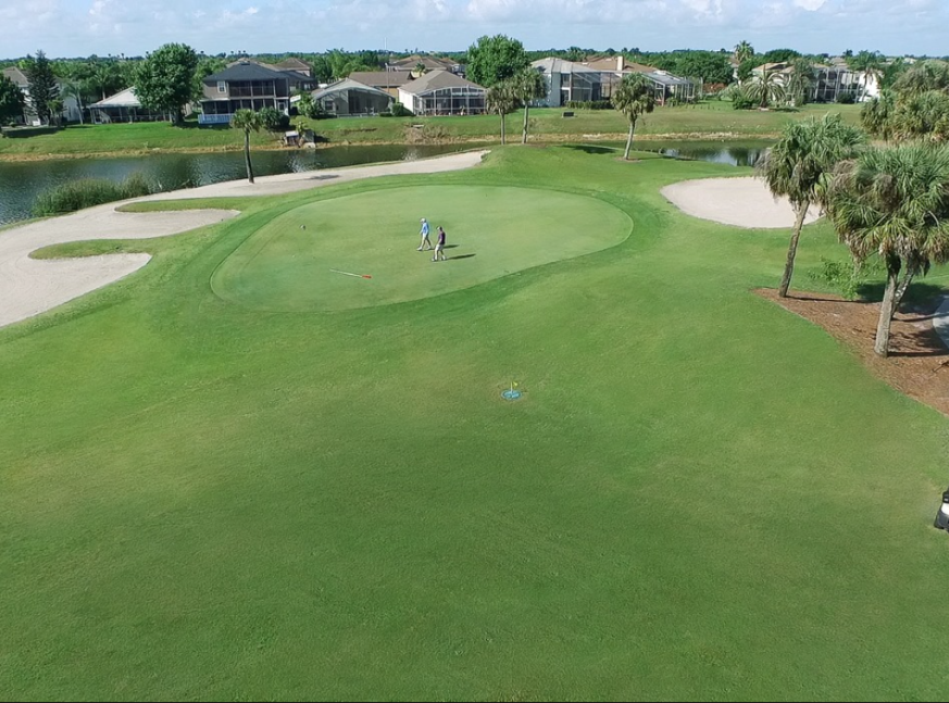 two people playing golf on a golf course with trees, lakes, and houses - remington golf club kissimmee