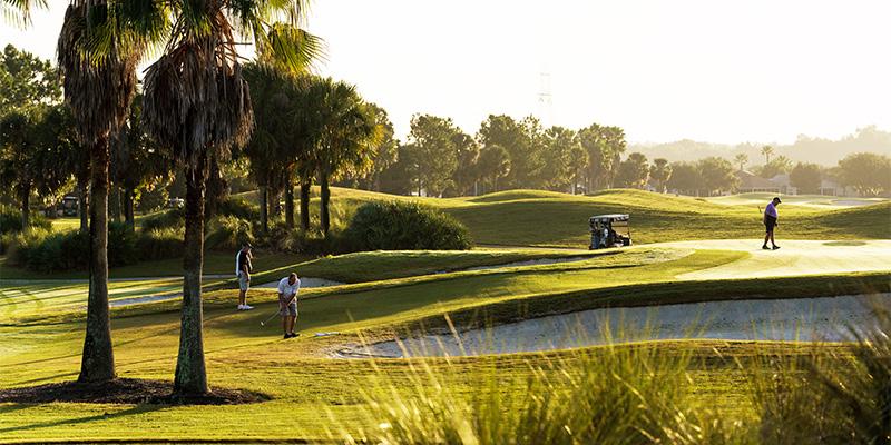 On the golf course, there are three golfers and a golf cart - Havana Country Club