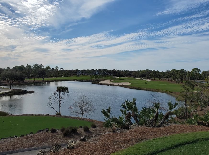 The golf course features a large lake and numerous trees - Calusa Pines Golf Club
