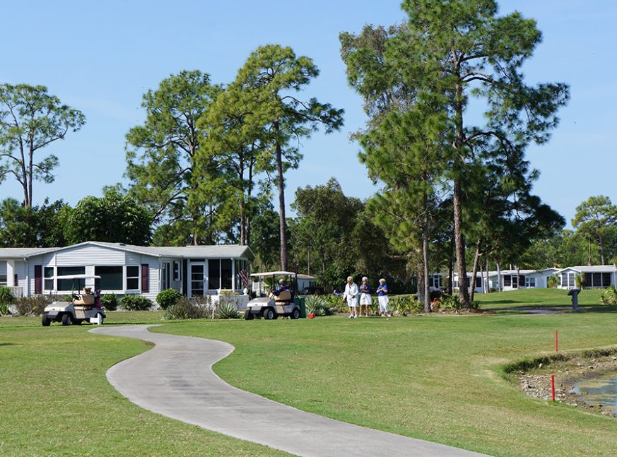golfers playing in golf course with homes behind - Pine Lakes Country Club