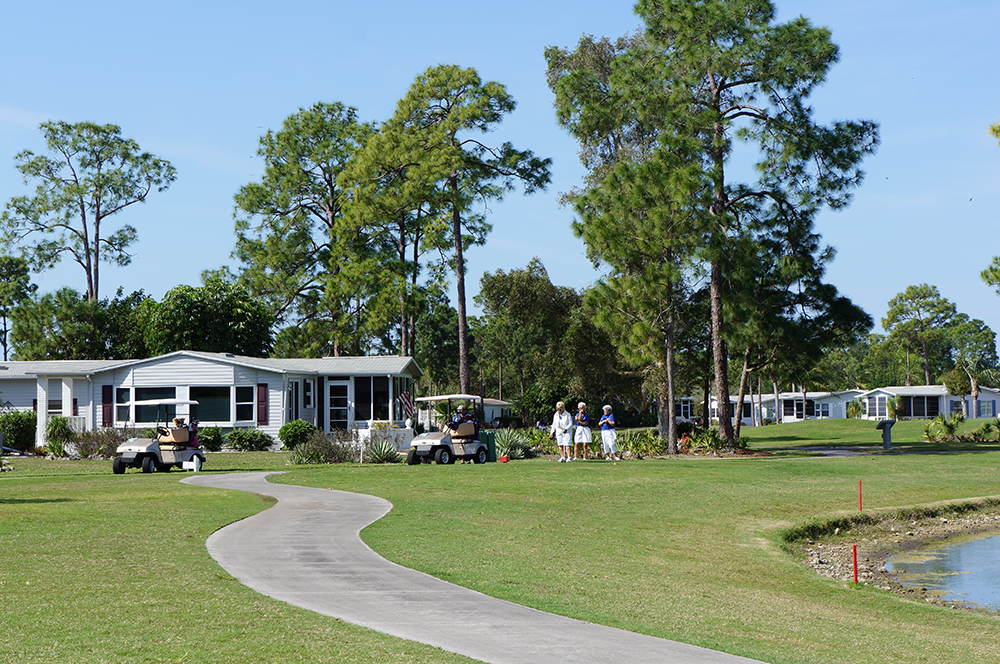 golfers playing in golf course with homes behind - Pine Lakes Country Club